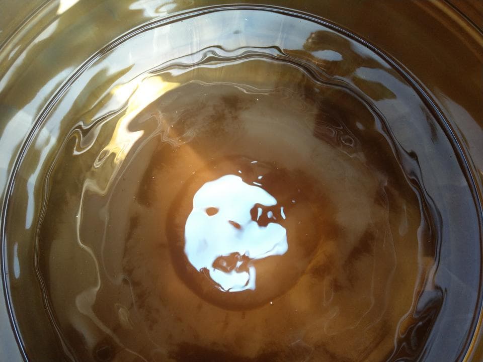 1) 照片顯示一個裝滿棕色液體的玻璃碗,液體表面有一層薄薄的白色泡沫