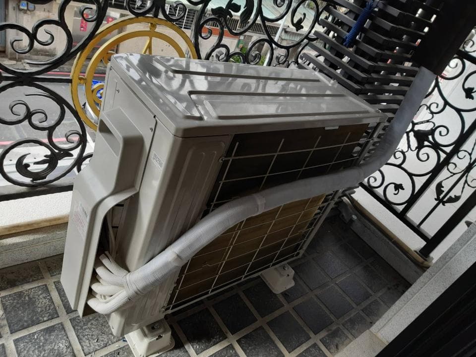 1) 照片中是一台白色室外機,安裝在鐵欄杆的下方