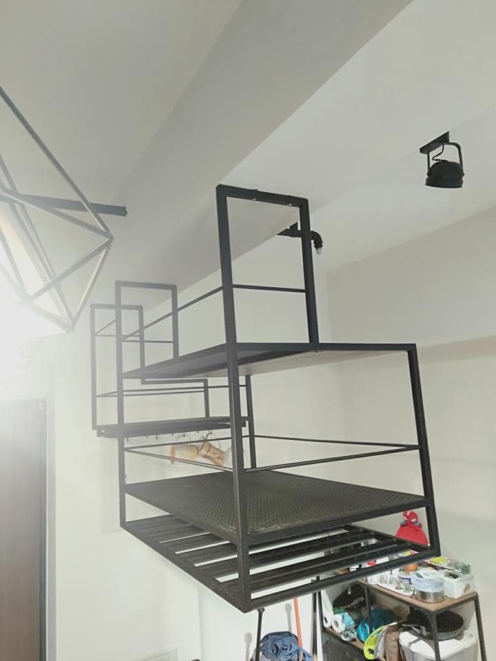 1) 照片顯示一個黑色金屬架,安裝在房間的牆壁上,架子上有一個網狀層板