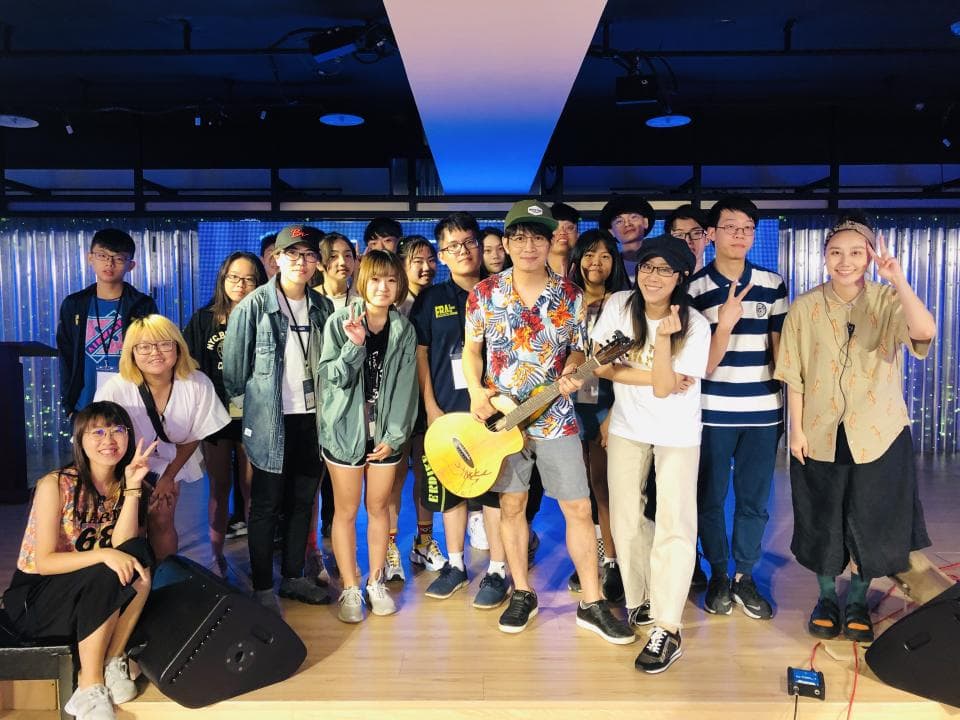 這張照片是一群朋友在室內聚會,最重要的是他們正在歡快地唱歌,其中一人還拿著吉他伴奏,充滿青春活力。