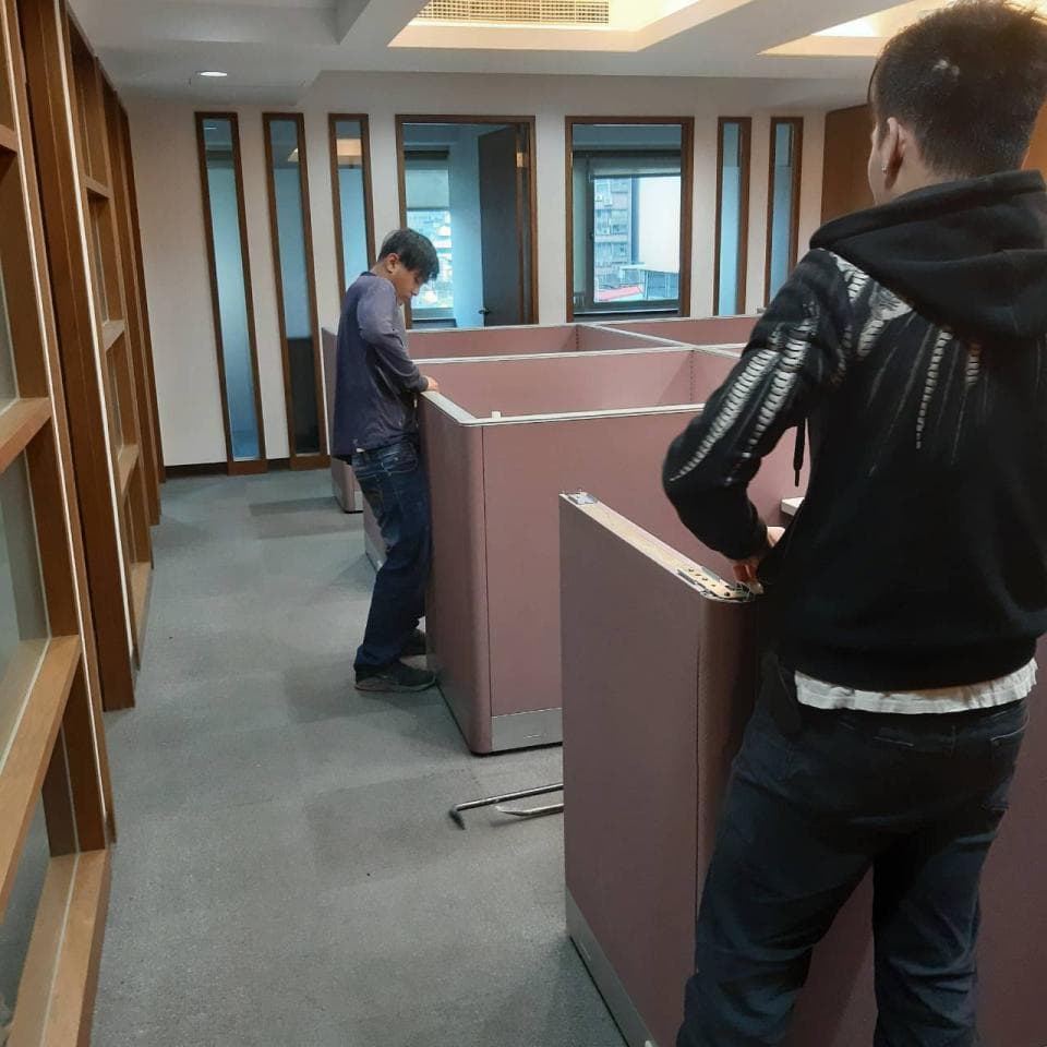 1) 照片顯示兩個人在一個辦公室裡,一個人站在辦公桌旁,另一個人站在辦公桌前,看著辦公桌