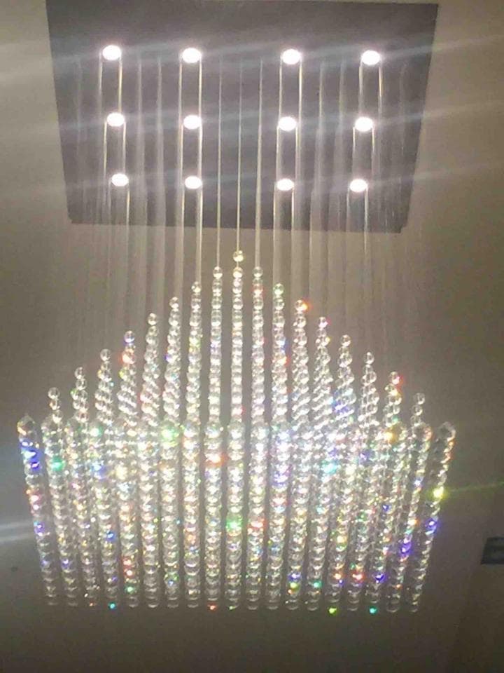 1) 照片顯示一個大型水晶吊燈,有許多水晶珠串,從天花板垂下,形成一個三角形狀