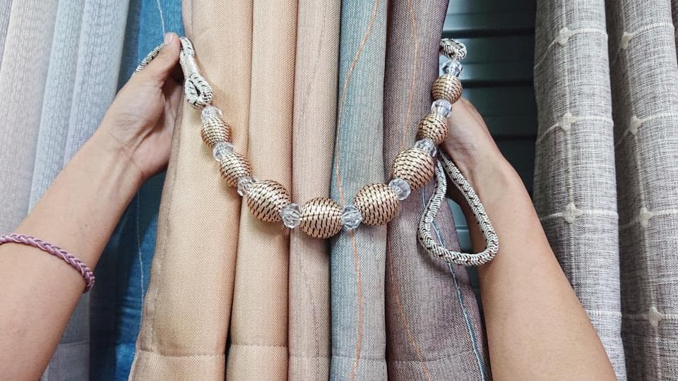 1) 照片顯示一隻手拉著窗簾的綁帶,綁帶是用金屬珠子和繩子串起來的