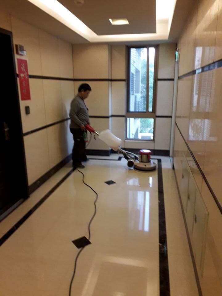 1) 照片顯示一名男子正在使用地板拋光機清潔大理石地板,地板上有黑色的邊條,背景是一間大理石牆面的走廊