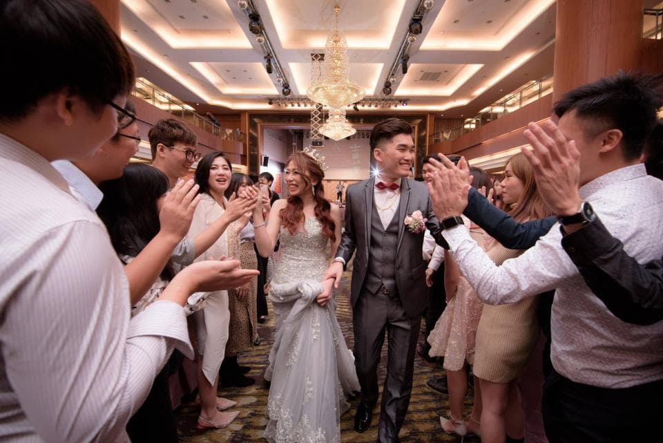 這張婚禮照片是一對新人在賓客的掌聲和歡呼聲中,步入宴會廳。
