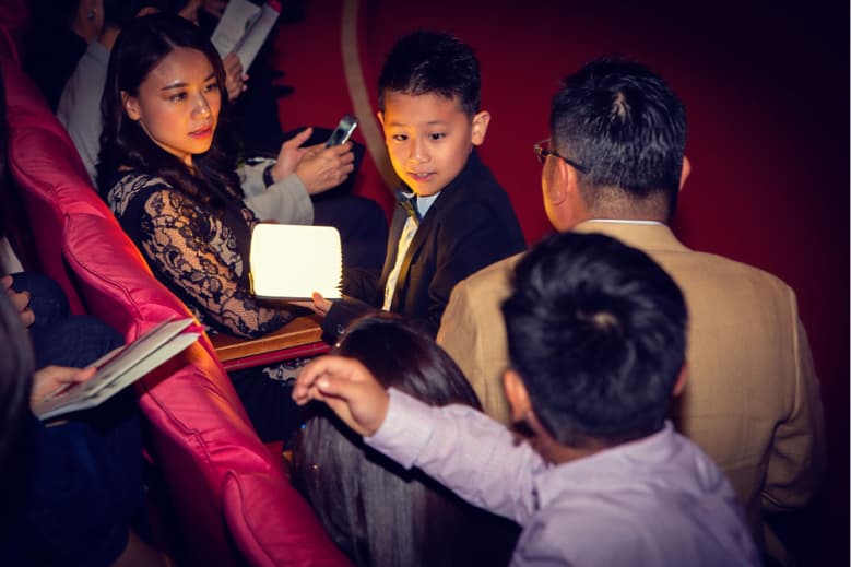 這張照片是一群人在一個昏暗的房間裡,其中一個人拿著一個發光的燈。