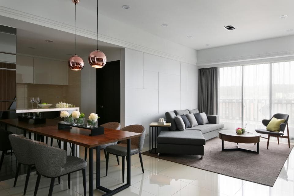 這張照片是一個現代化的客廳,有著灰色沙發、一張木頭茶几和三個銅色吊燈。