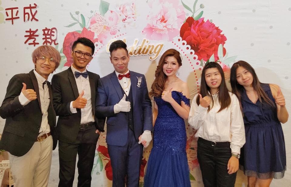 這張「婚禮」的照片是四位朋友站在一起,其中兩位男生穿著西裝,一位女生穿著婚紗,另一位女生穿著洋裝。