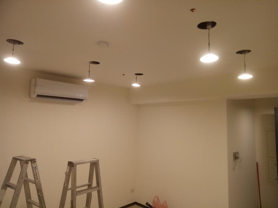 這張照片是一間簡約風格的房間,房間裡有一台冷氣,兩個梯子,以及一些燈光。