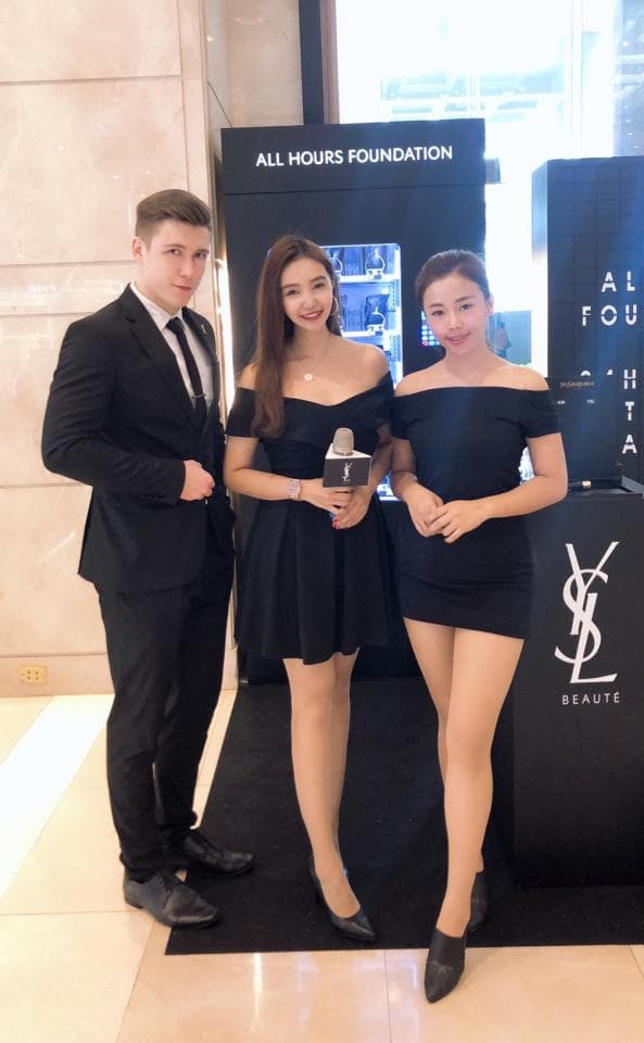 1) 這張照片展示了三位年輕人站在 YSL 化妝品櫃台前,中間的女孩手持麥克風,看起來像是正在進行商品宣傳活動