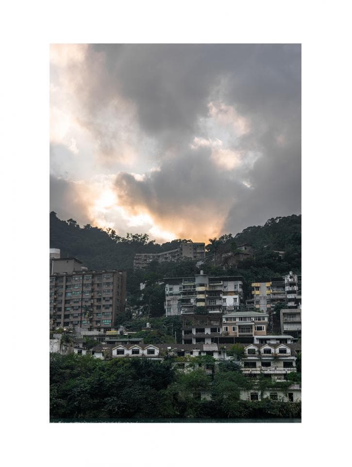 這張「山坡上的住宅」的照片是,在一片雲霧籠罩的傍晚,有著層層疊疊的房屋建築,房屋大多是灰色的,在山坡上形成了一道風景線,背景是夕陽照射下的天空,顯得格外寧靜祥和。