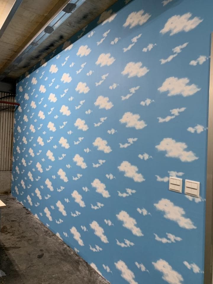 1) 照片顯示一間房間的牆壁上貼著帶有白色雲朵的藍色壁紙