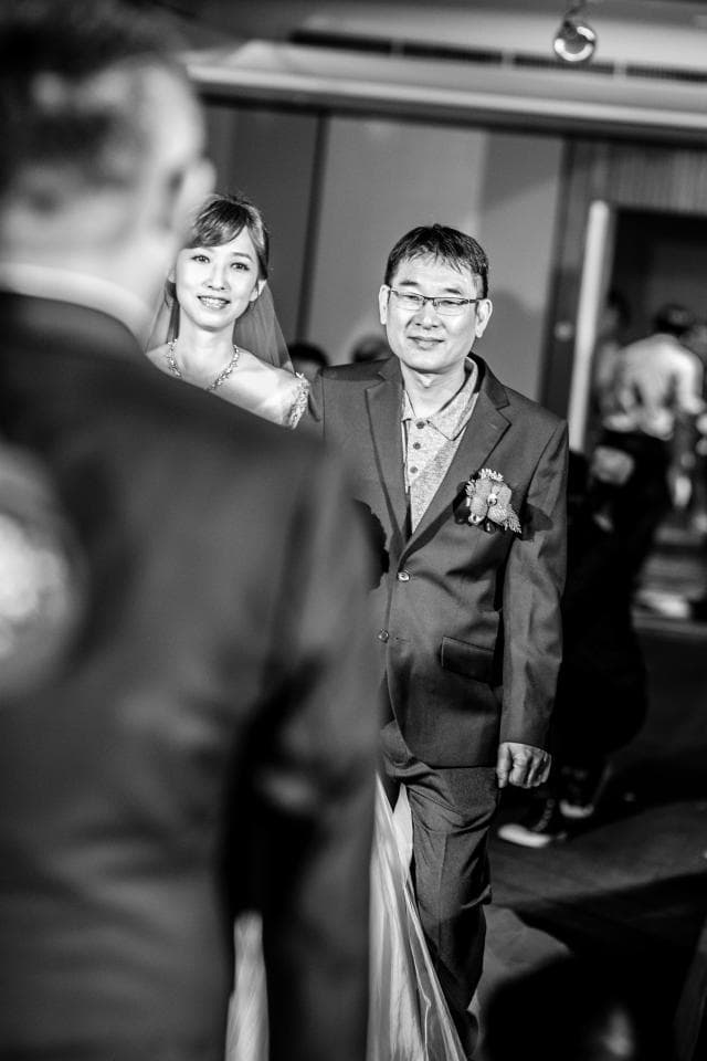 這張照片是新郎新娘在婚禮現場,新郎穿著西裝,新娘穿著婚紗,他們看起來很幸福。