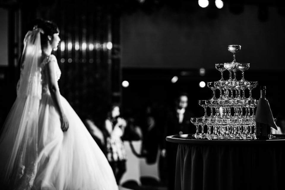 這張婚禮的照片是一個新娘走過一個香檳塔。