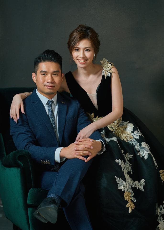 這張「婚紗照」的照片是一對新人在深色背景下,男士穿著深藍色西裝,女士穿著黑色蕾絲婚紗,兩人互相依偎,展現甜蜜的幸福。