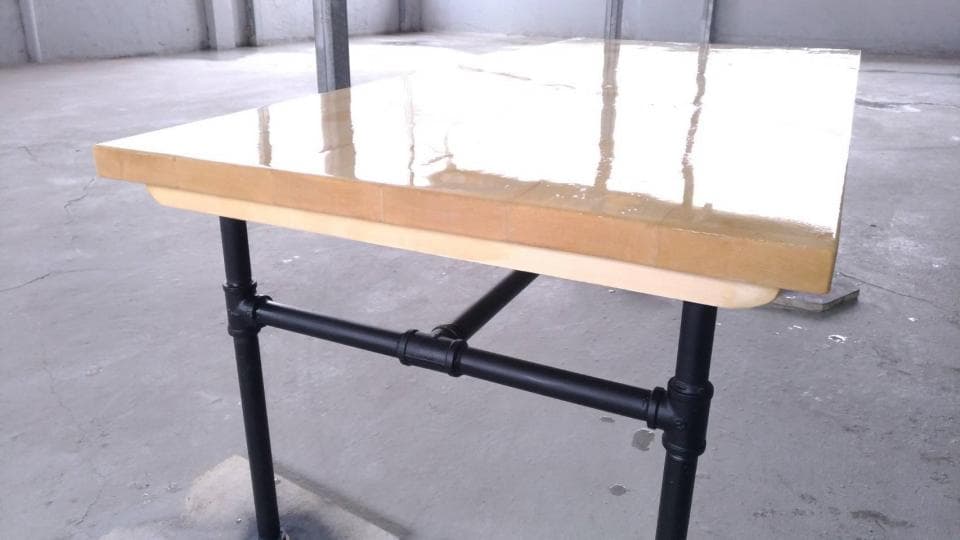 1) 這是一張木頭桌子,桌面是淺色的木頭,邊緣光滑,桌腳是黑色的金屬管,桌子看起來很堅固