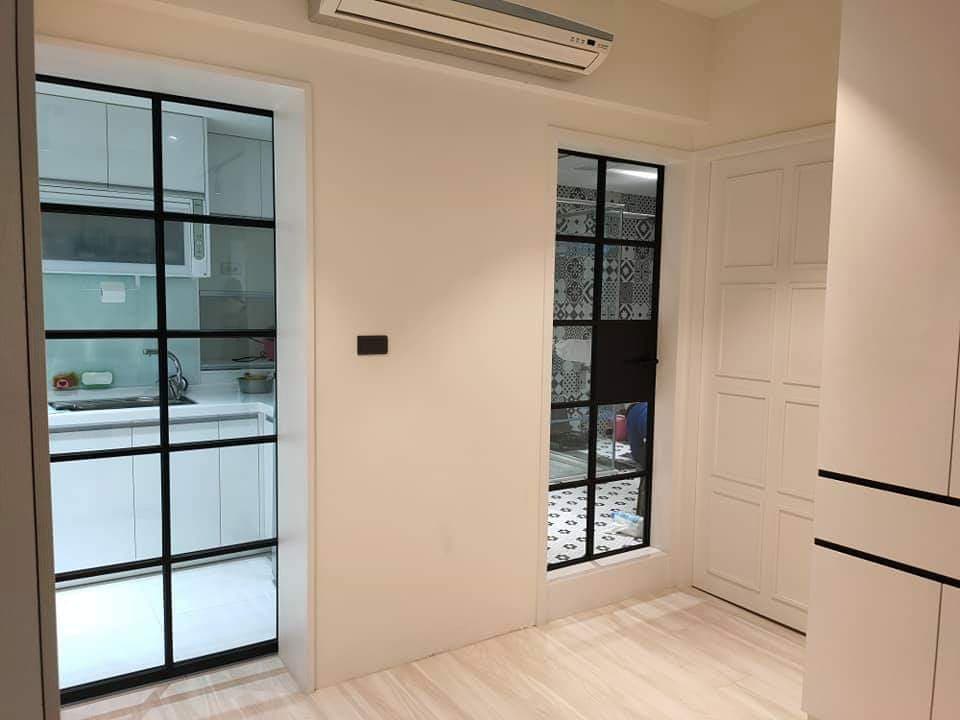 1) 照片顯示一間現代化的公寓,裡面有兩道門,一道是黑色金屬框架的玻璃門,通往廚房,另一道是白色木門