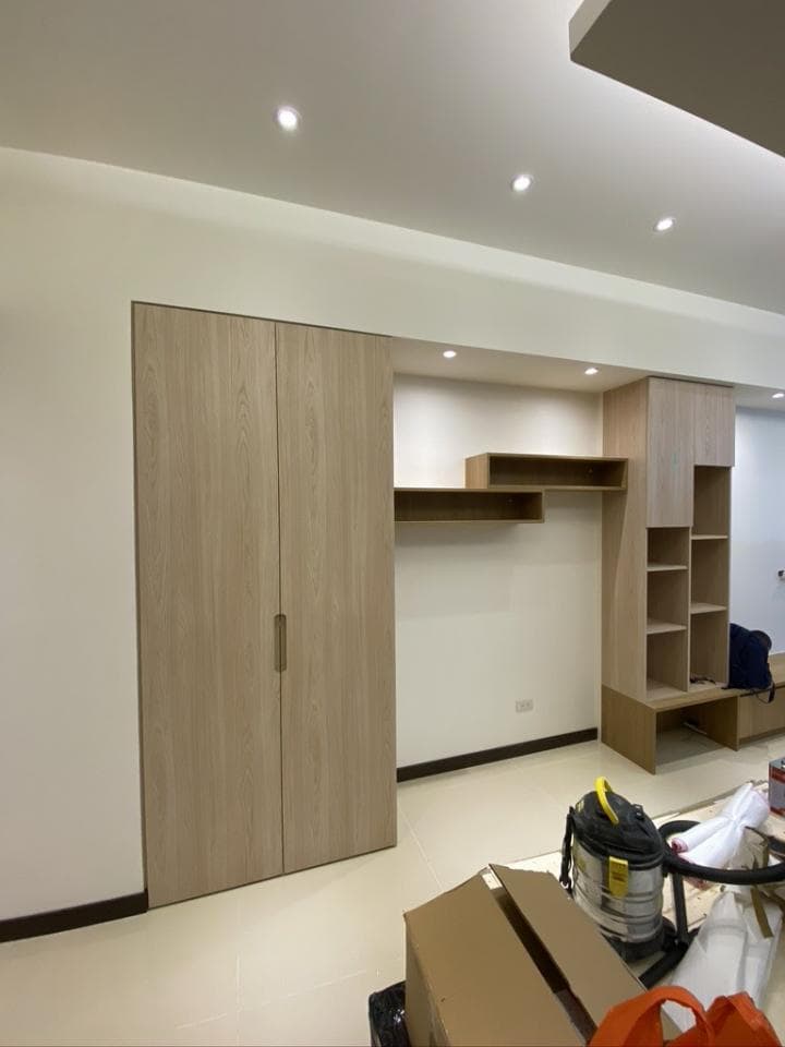 1) 照片展示了一個現代化的客廳,其中有木質的雙開式衣櫃、嵌入式的壁櫃、白色的天花板,以及嵌入式的照明燈