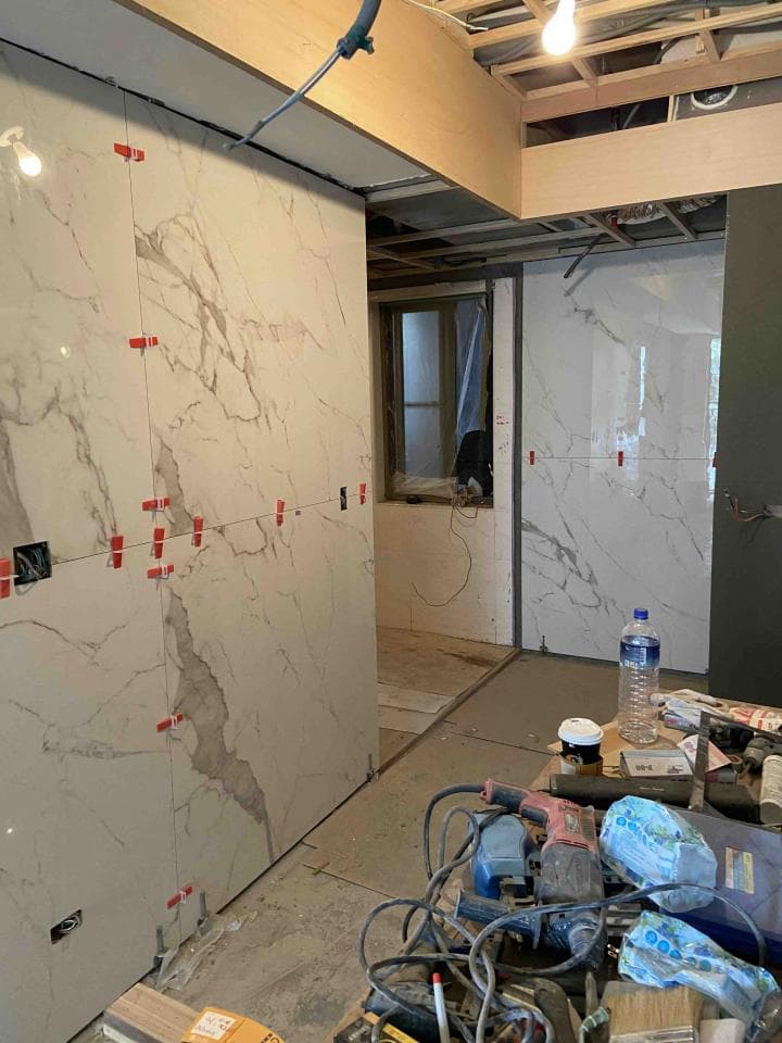 1. 照片顯示一個正在進行裝修的房間,房間的牆壁上貼著白色的磁磚,牆上還貼著紅色的標籤