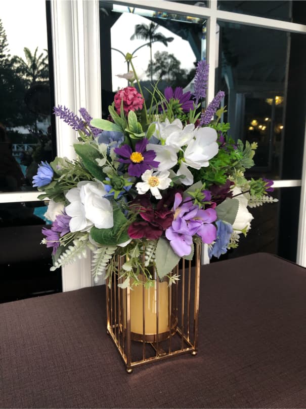 這張照片是一束色彩繽紛的鮮花,擺放在金色鐵架花瓶裡,襯托出花朵的嬌豔。