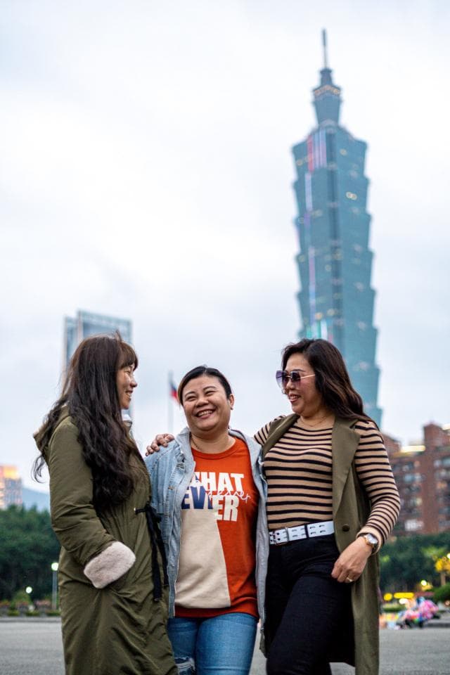 這張照片是三位女性朋友在臺北101大樓前開心合影,她們穿著時尚,表情自然,展現出友誼的溫暖和都市的活力。