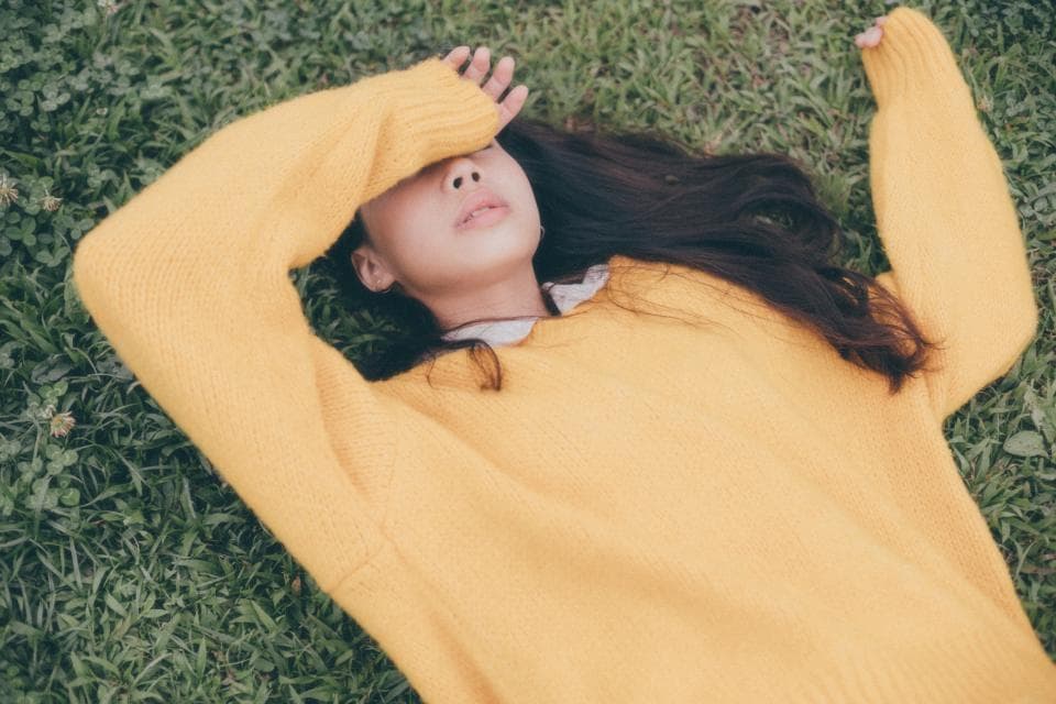 這張「女子躺在草地上,戴著黃色毛衣,閉著眼睛」的照片是。