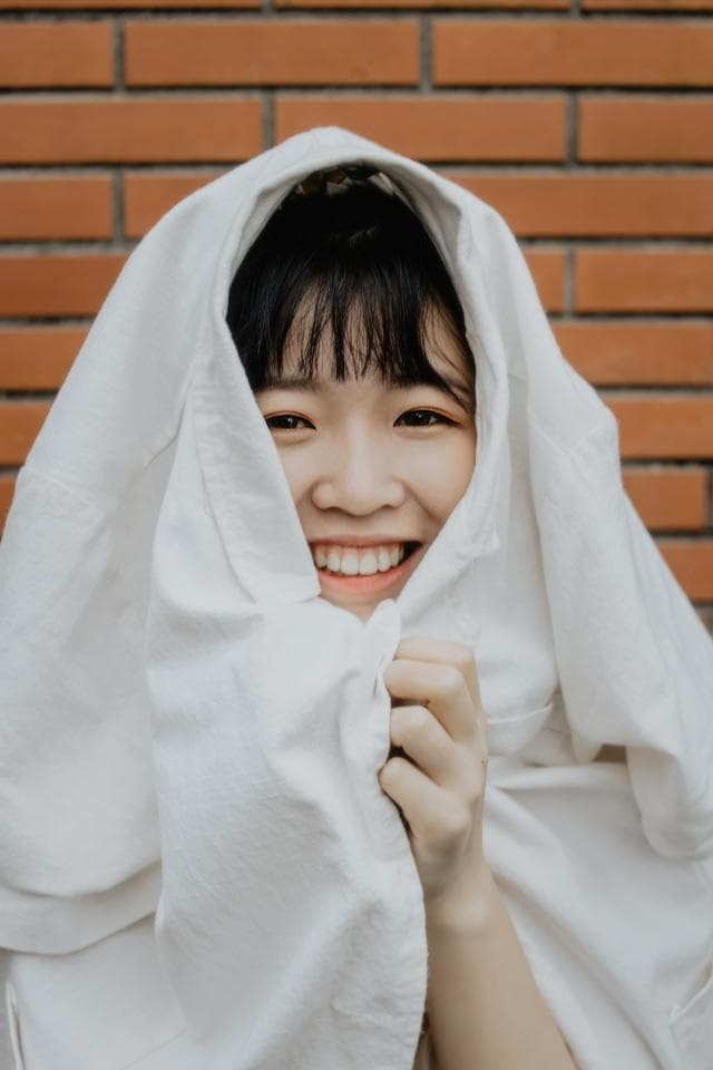 這張照片是一個年輕女孩穿著白色衣服,她露出燦爛的笑容,她的眼睛看起來很開心。