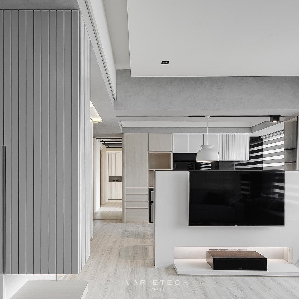 這張照片是一間現代化的客廳,最顯眼的地方是一個大型的電視機牆,牆上掛著一臺平板電視,下方有一個白色的電視櫃,並擺放了一個黑色的音響系統,整體設計簡潔時尚。