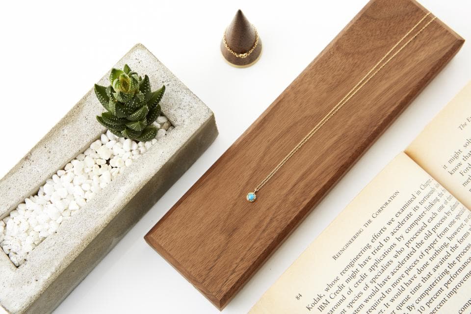 這張「擺滿綠色植物盆栽、木製託盤和金色項鍊」的照片是,顯示了一種簡約的風格,帶有自然和現代的元素。