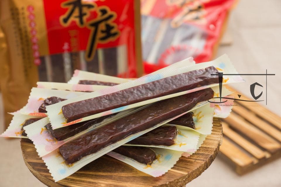 這張「牛肉乾」的照片是一包牛肉乾放在木頭盤子裡,上面有花紋的包裝紙,看起來很美味。