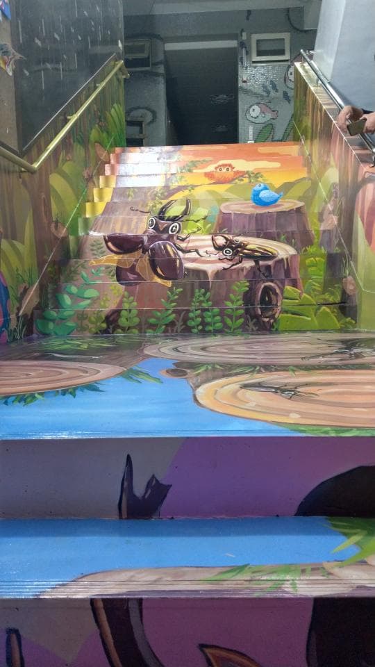 這張照片是一條彩繪的樓梯,上面畫著昆蟲、樹木和花草。