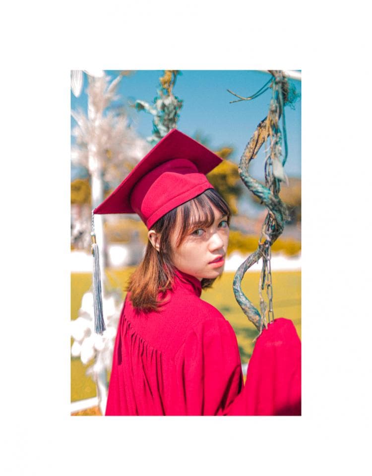 這張「畢業照」的照片是一個女孩,她穿著紅色畢業袍,戴著紅色畢業帽,看起來很開心。