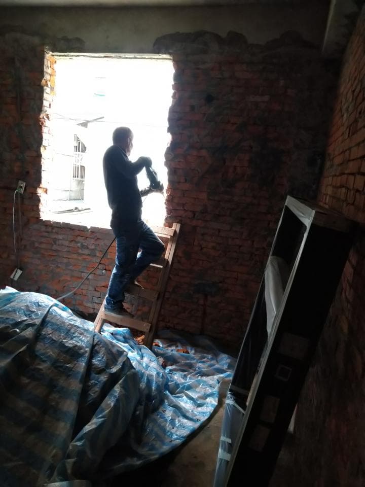 這張照片是一個正在進行中的室內裝修工程,其中最重要的是工人正在拆除牆上的磚塊。