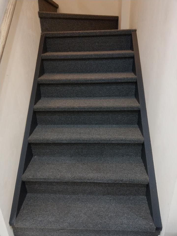 1) 照片展示的是一個灰色的樓梯,樓梯上有地毯,樓梯的邊緣是黑色的