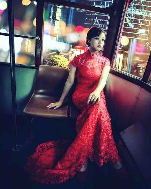 這張「婚紗照」的照片是一名女子穿著紅色婚紗,坐在香港電車裡,背景是香港街景。