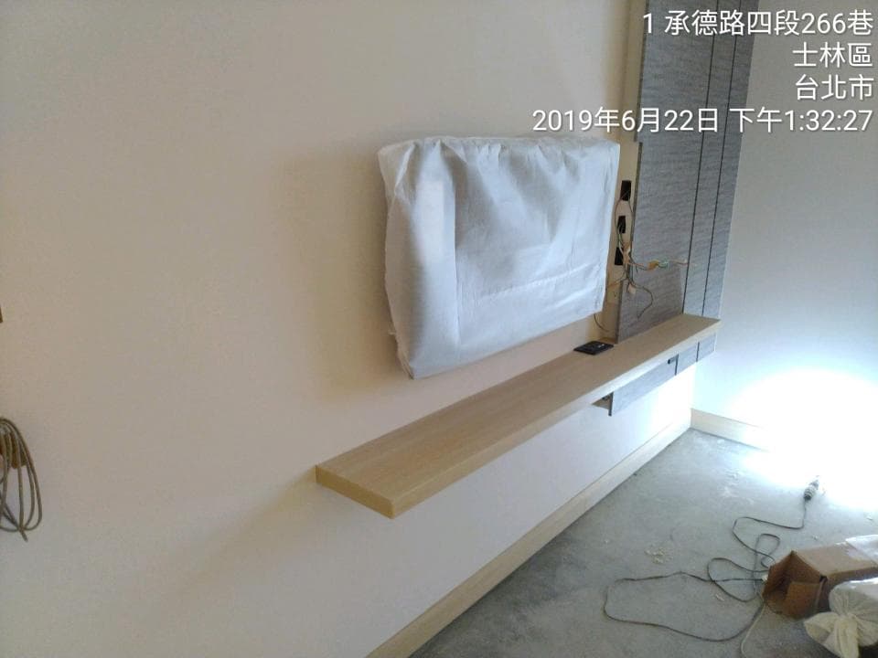 這張照片是一台電視的安裝過程,照片重點是電視下方新裝的電視櫃,材質看起來是木頭。