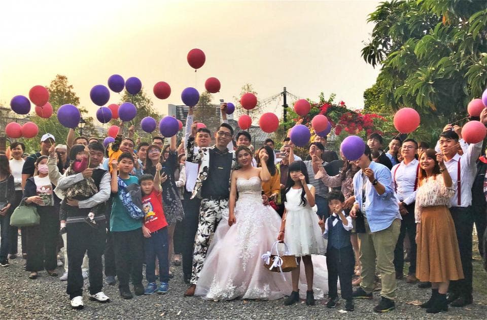這張「婚禮」的照片是一對新人和親朋好友們一起站在戶外,舉著氣球拍照的畫面。