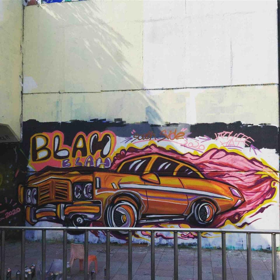 這張照片是一面牆壁上的塗鴉,塗鴉裡有一輛黃色的汽車,汽車前面寫著 “Blah” 字樣。