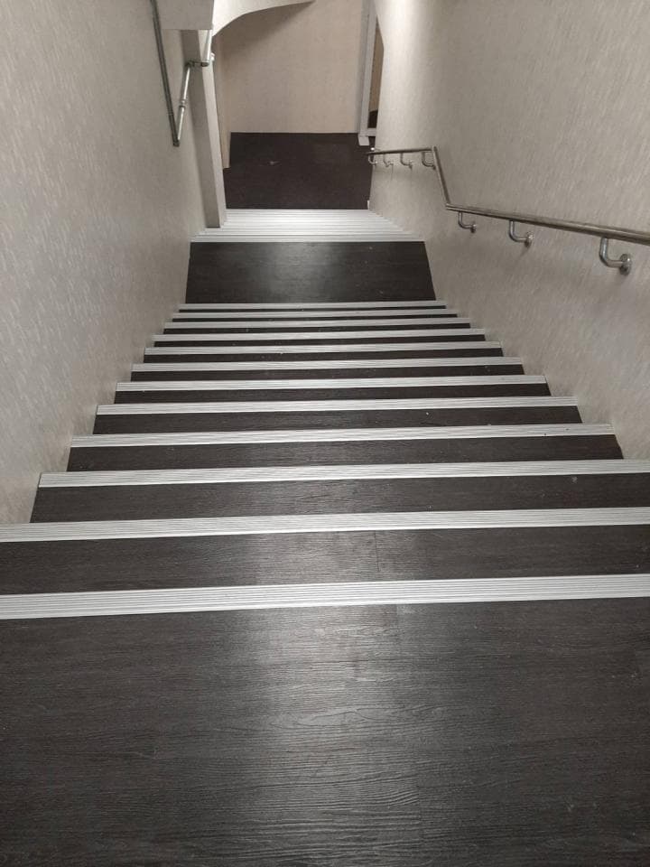 1) 這是一張由下往上拍攝的樓梯照片,樓梯上有木質地板和白色邊條,樓梯扶手是金屬材質,背景是白色牆壁