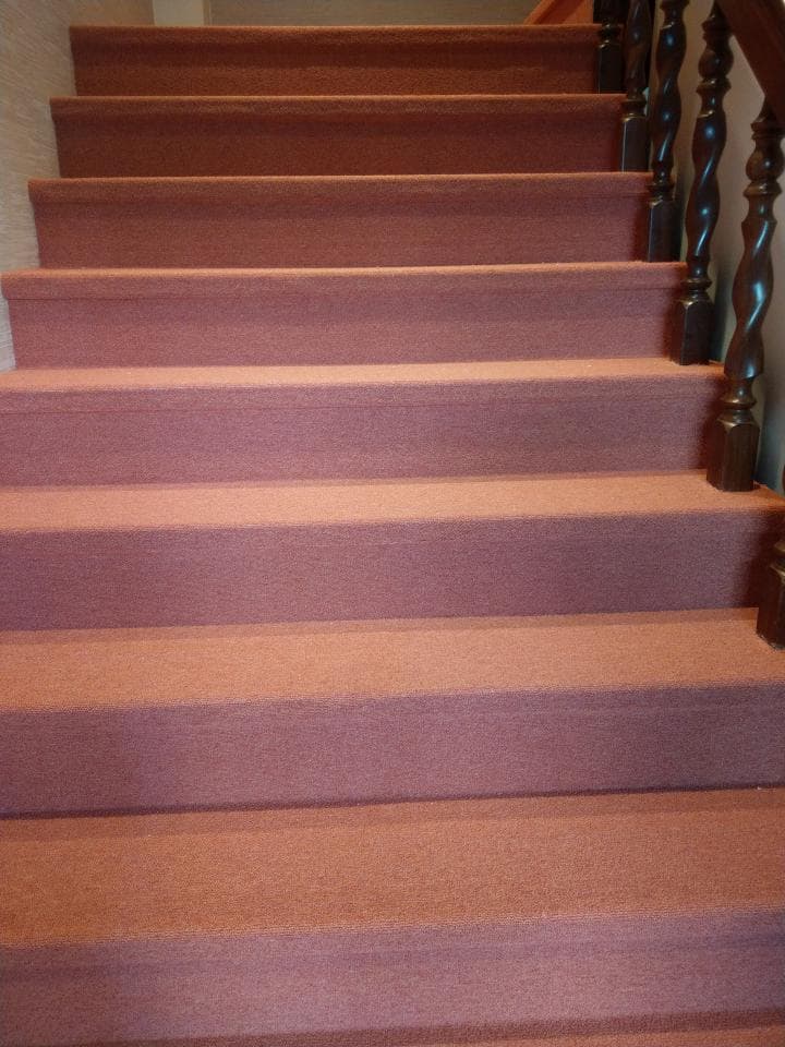 1) 照片顯示一個木質扶手的樓梯,樓梯上有粉紅色地毯