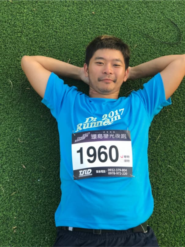 這張「跑步」的照片是一個穿著藍色運動服的男生,他躺在綠色的草地上,他的胸口上有一個標籤,上面寫著「1960」。