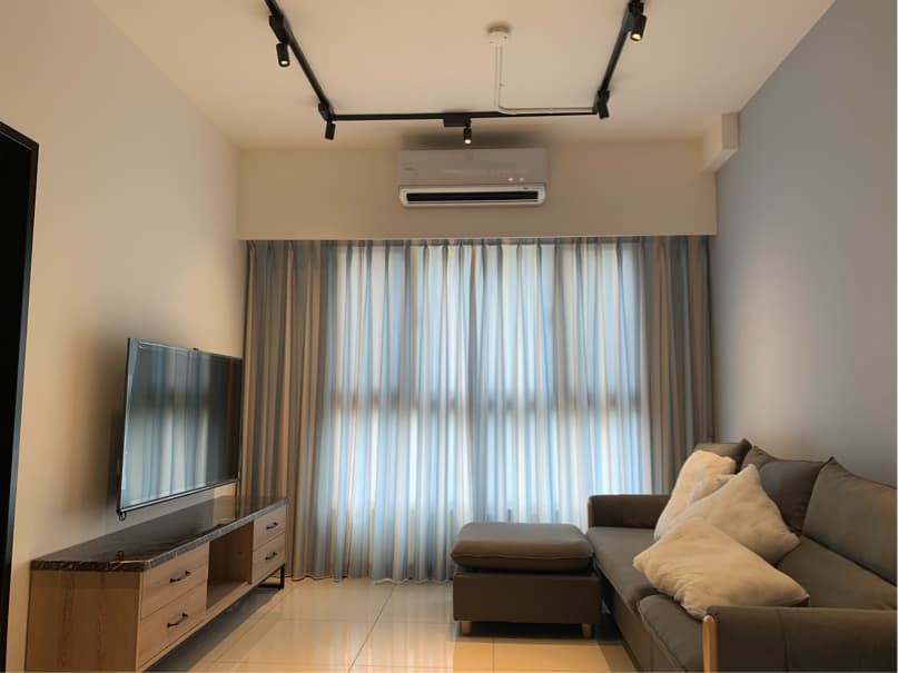 這張照片是一間客廳,最重要的部分是沙發和茶几。沙發是灰色的,有兩個靠枕,茶几是深棕色的,是木質的,看起來很舒適。