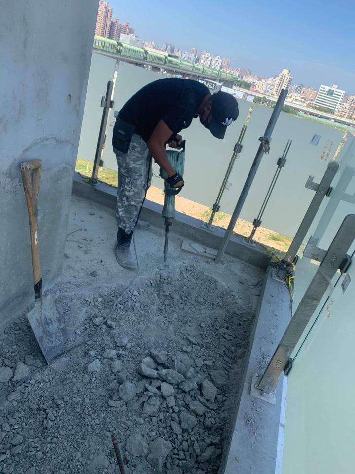 1. 照片顯示一名男子正在使用破壞錘拆除水泥地面