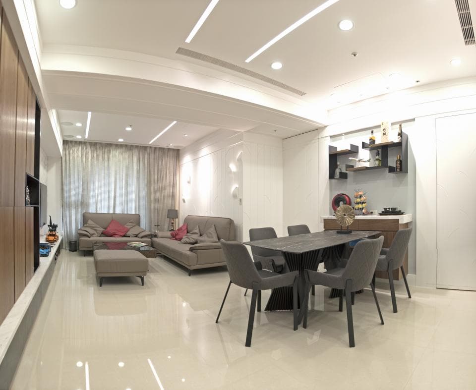 這張照片是一個現代化住宅的客廳和餐廳。客廳有一個灰色的沙發,而餐廳則有一張大餐桌,周圍有六張椅子。