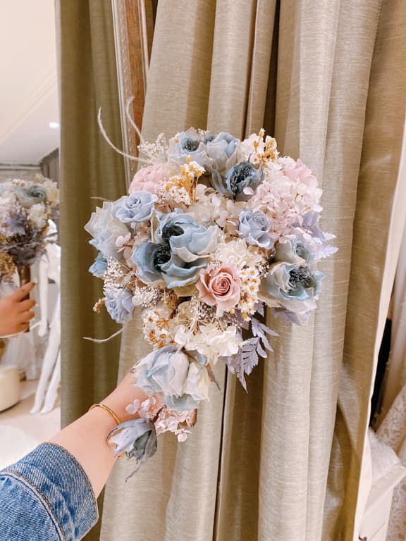 這張照片是一束乾燥花,以淡藍色、淡粉色和米白色為主色調,花朵被精心排列成圓形,營造出浪漫優雅的氛圍。