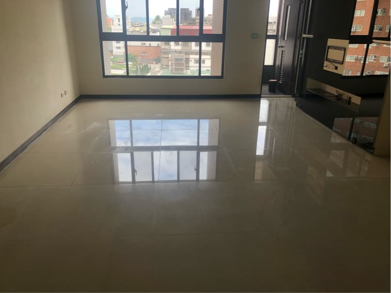 1) 照片顯示一個帶有大型窗户的空房間,地板上鋪着光滑的瓷磚,地板反射著窗外景色的光線