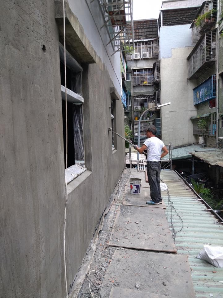 這是一張建築工人正在水泥牆上塗抹水泥的照片