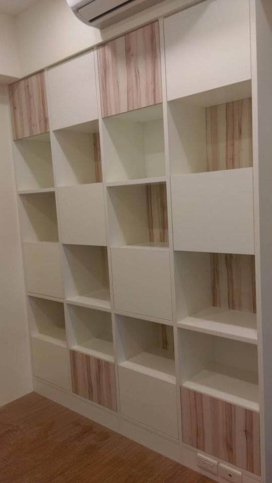 這張照片是一個現代化的書架,它由白色和木紋色板材組成,有著簡潔的線條和多層的設計,讓人感到舒適且美觀。