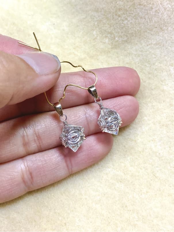 1) 照片顯示一雙銀色的耳環,耳環上裝飾著透明的水晶,水晶看起來像是被包裹在一個精緻的銀色網狀結構中