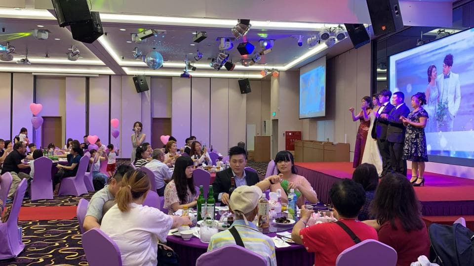 這張照片是婚禮宴會現場,臺上有一對新人正在舉行婚禮儀式,臺下賓客歡聚一堂,熱鬧非凡。